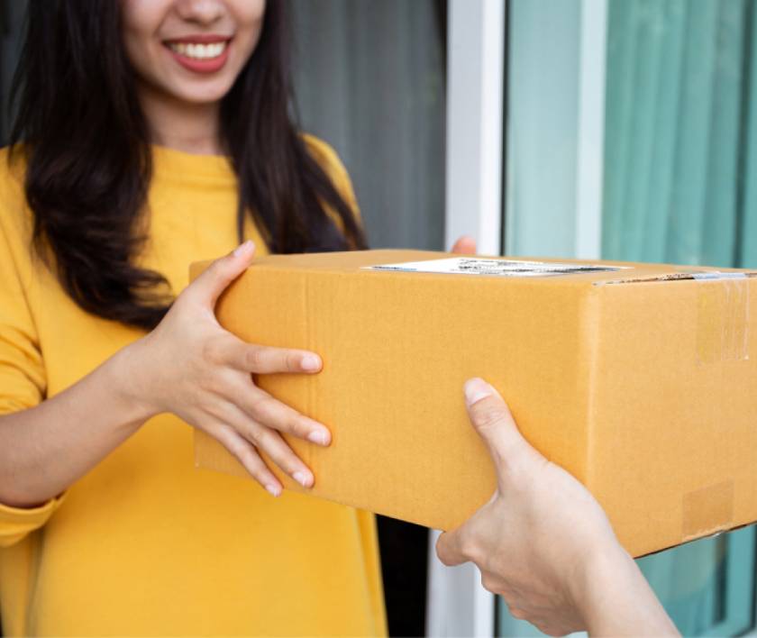 woman receiving parcel from delivery person at front door